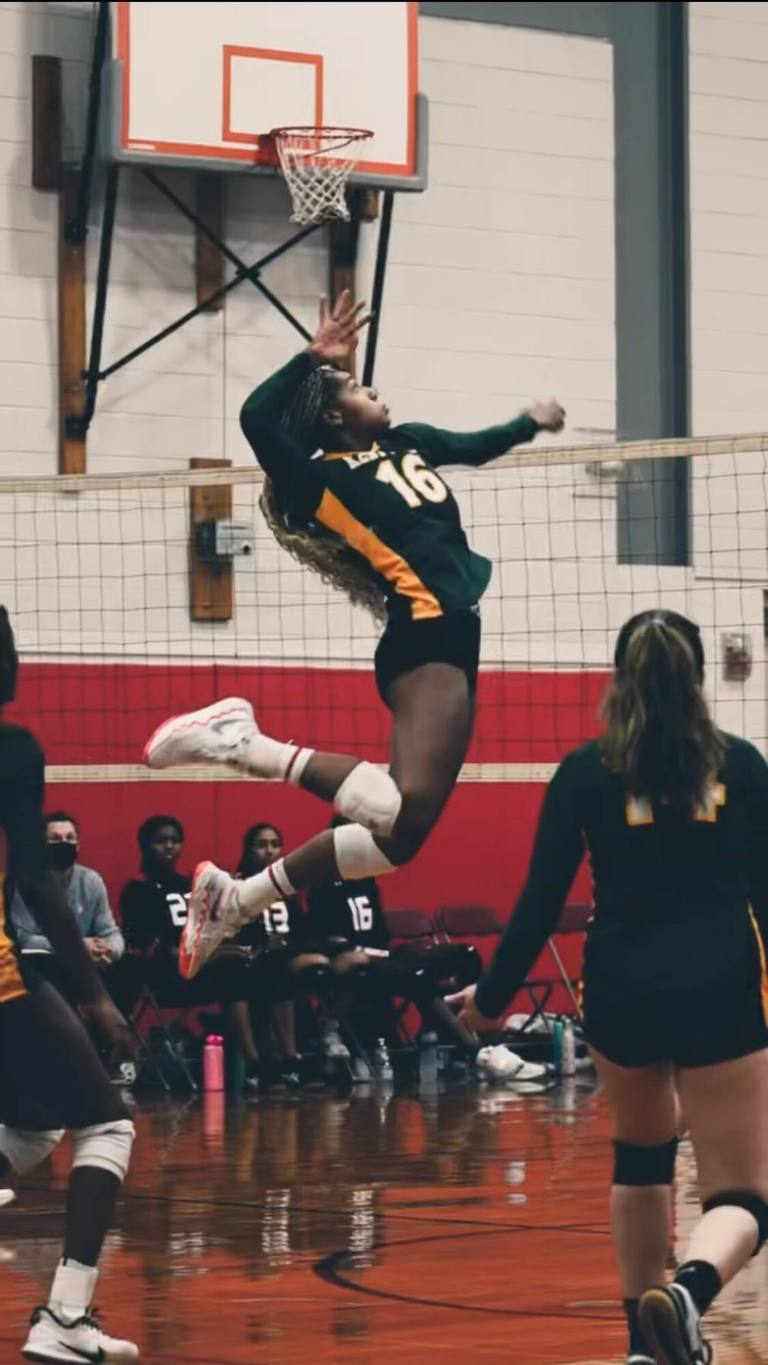 A Farm athlete rising to the rim, fully extended, in a packed gym