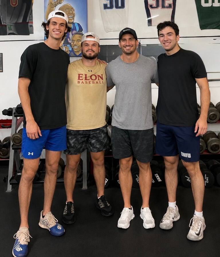 Four adult clients standing together on the training floor between sets
