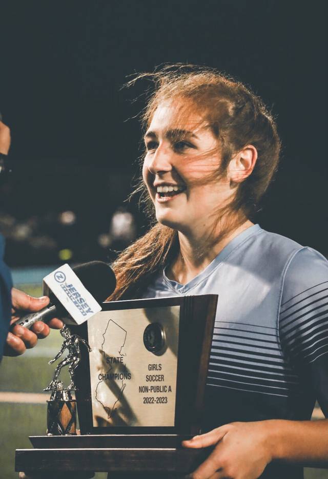 A smiling player holding the state-championship trophy plate during a postgame interview