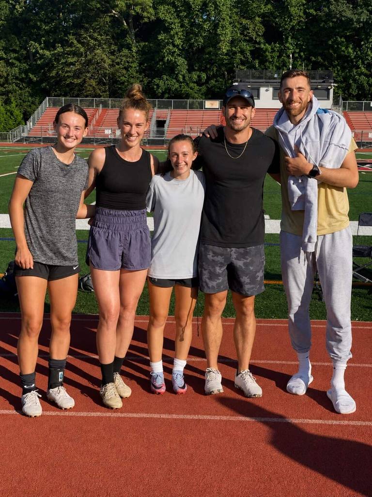 Ryan Nie trackside with four of the athletes he trains