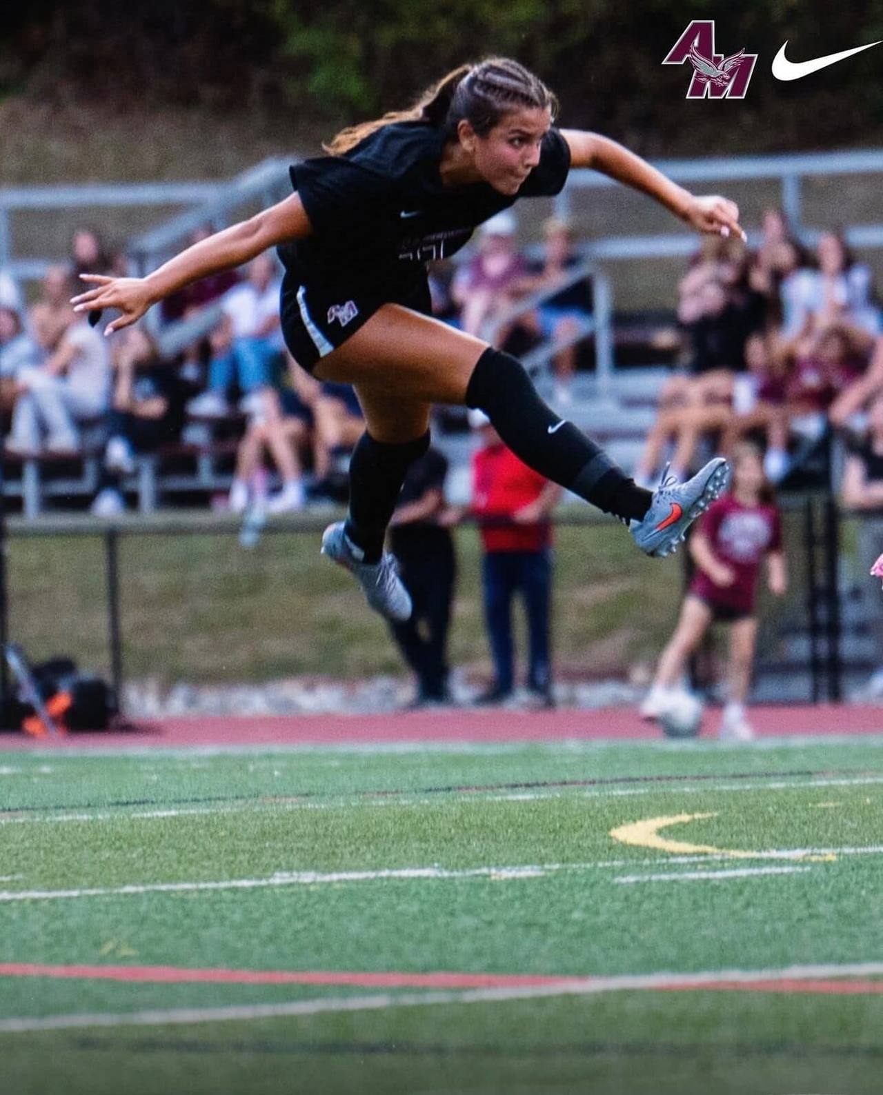 A Farm athlete striking a ball at full stretch under the lights