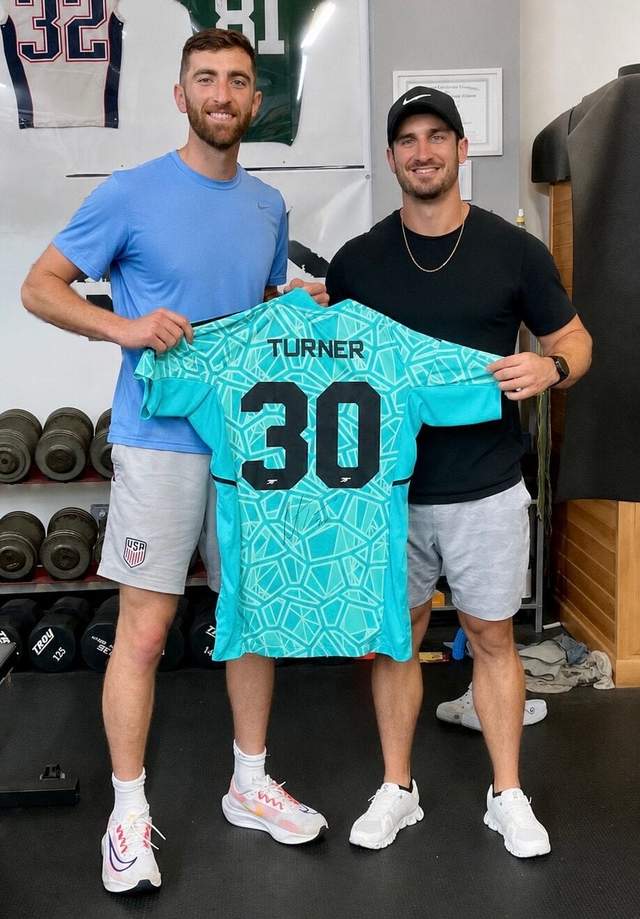 Ryan Nie in the gym with Matt Turner, holding up Turner's number 30 United States goalkeeper jersey